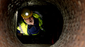 Kanalarbeiter in der Kanalisation schaut nach oben in einem Schacht